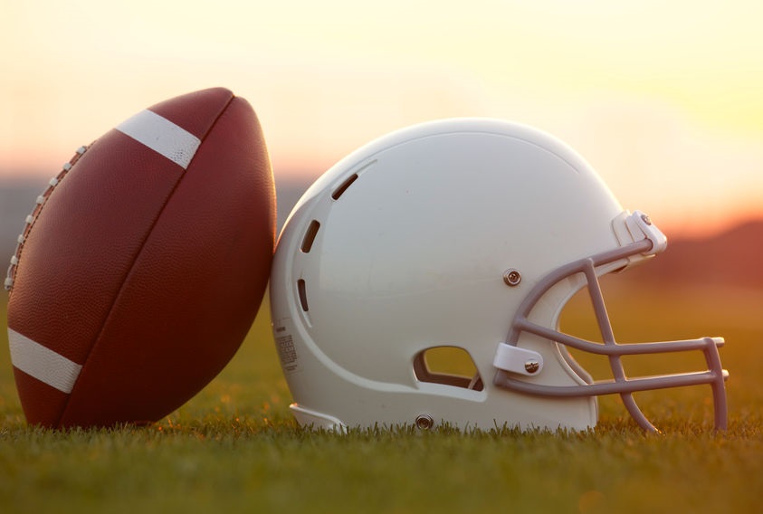 26507961 - american football and helmet on the field at sunset