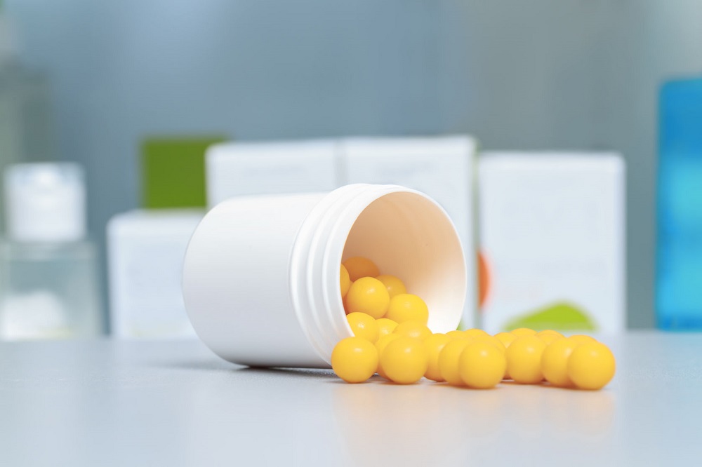 38306150 - placebo. plastic container with yellow gel capsules on a pharmacy counter